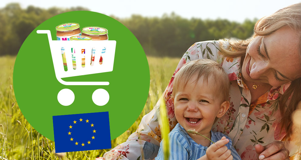 Naine ja laps istuvad põllul, kaasas ostukorv, milles on imikutoidu purgid ja Euroopa Liidu lipp.