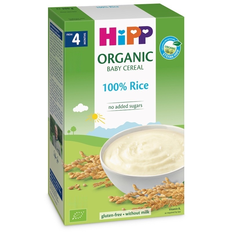 Rohelisel karbil on toote silt "Hipp Organic Baby Cereal", millel on pilt kausitäie valgeid beebimahlaid kuldsete riisiterade kõrval.