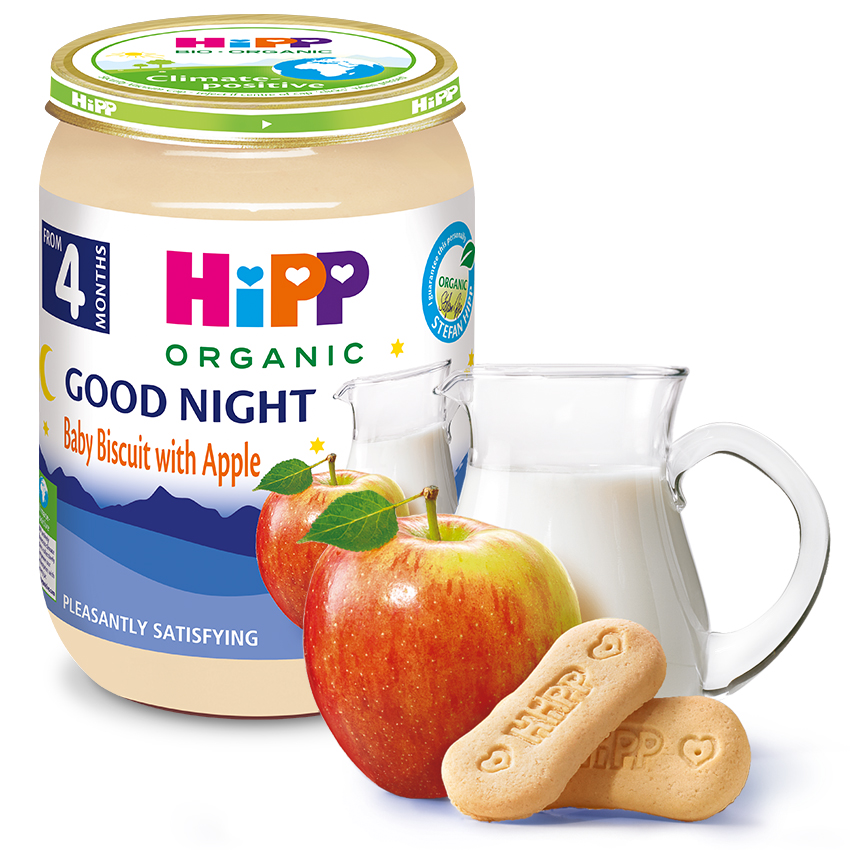 HiPP orgaanilise imikutoidu purgi, millel on märge "Good Night Baby Biscuit with Apple", kõrval on klaas piima, kaks küpsist ja õun.
